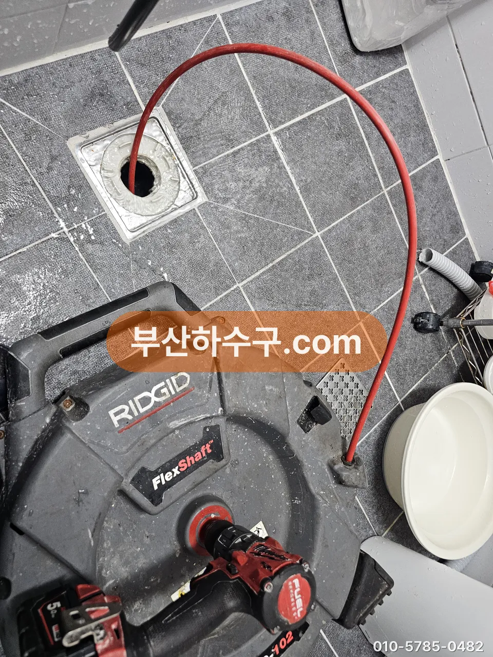 욕실 바닥 배수구에 드럼식 스프링 장비를 투입한 모습